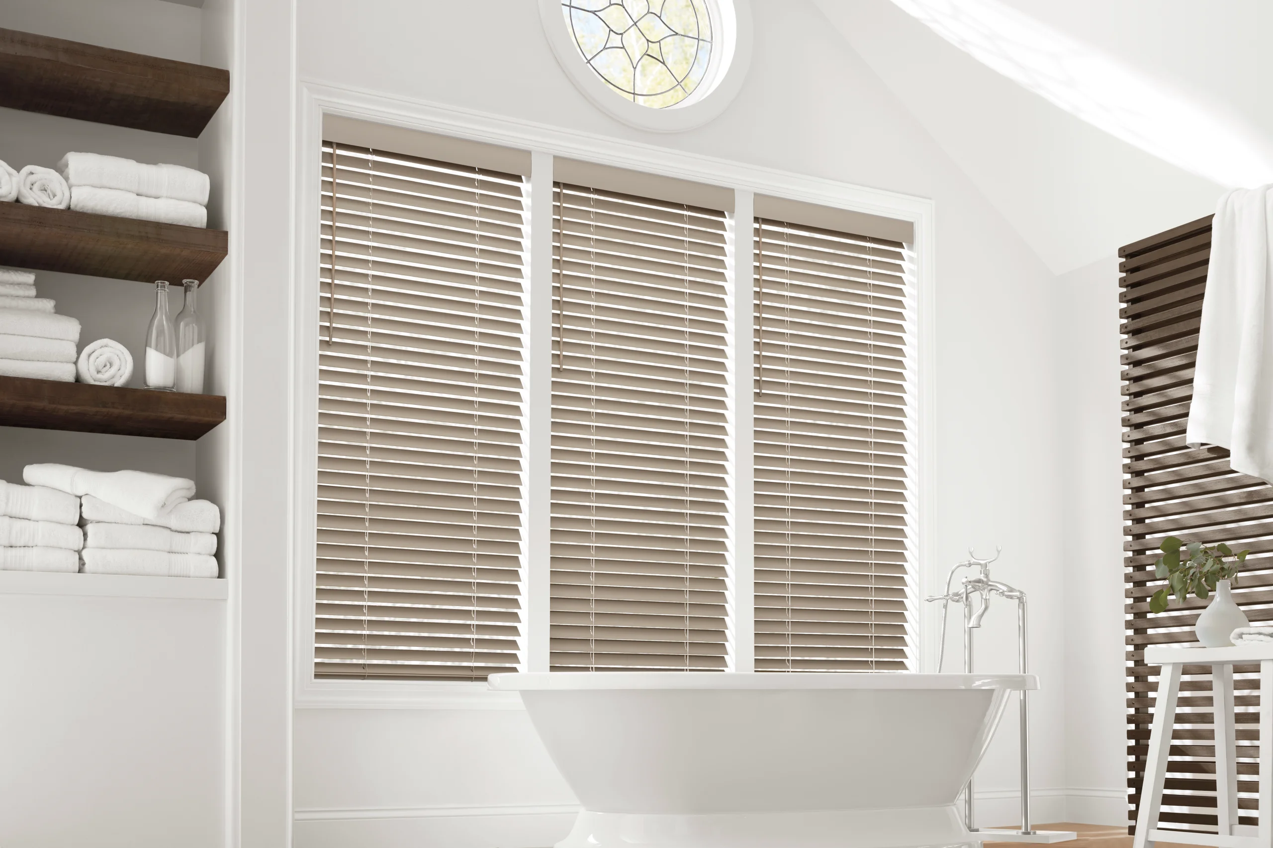 Hands dusting warm wood blinds in soft morning light, the kind of simple care that stretches a blind's lifespan.
