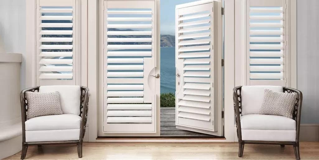 Plantation shutters framing French doors with a New England ocean view.