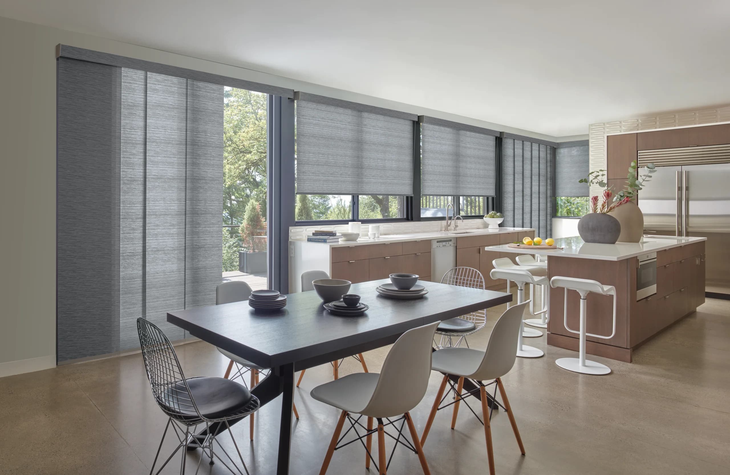 Designer Roller Shades running across a row of windows in a modern kitchen with walnut cabinets and a concrete floor.