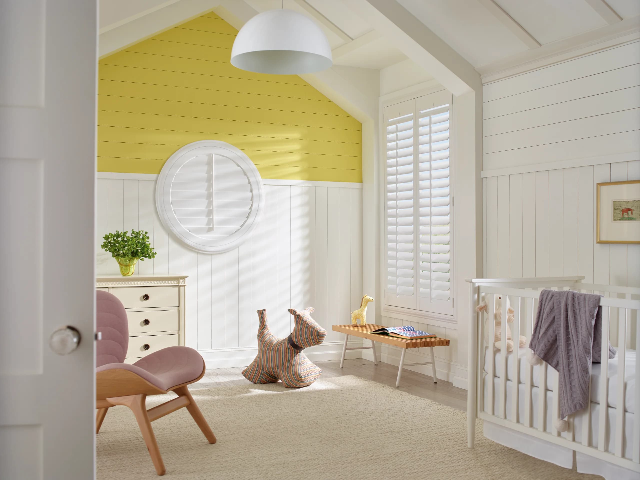 Hunter Douglas Heritance® Hardwood Shutters closed on a nursery window, with a round shutter fitted to a circular window on the far wall.