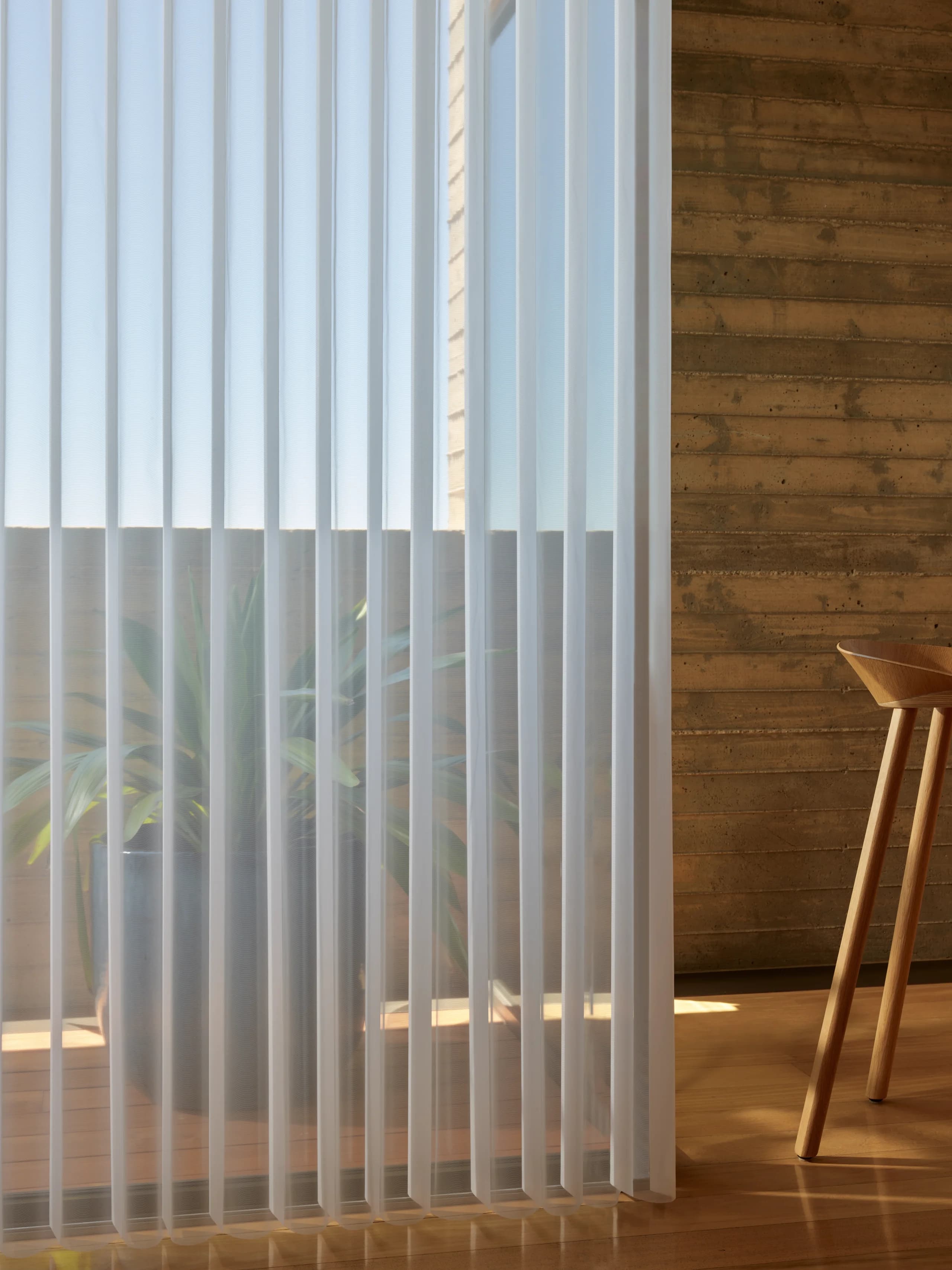 Close view of Hunter Douglas Luminette® Privacy Sheers, the vertical fabric vanes rotated to soften afternoon sun at a glass wall.
