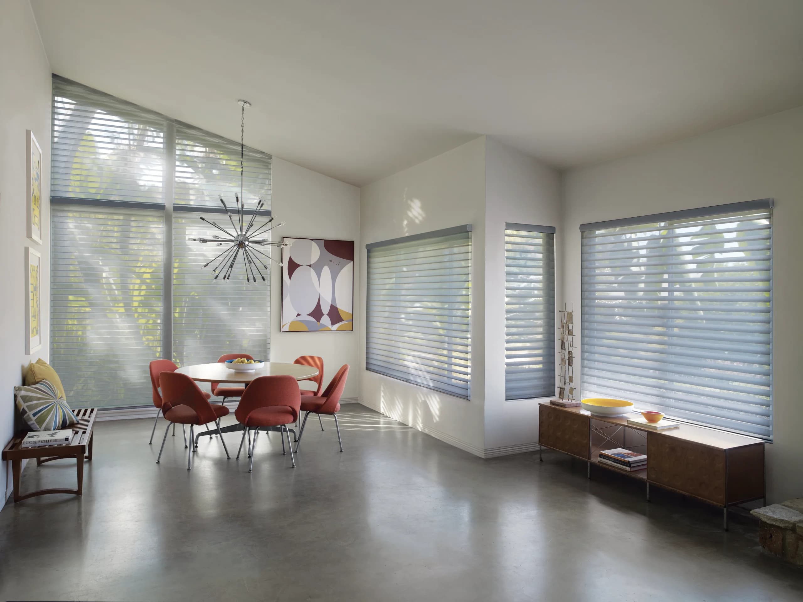 Hunter Douglas Nantucket™ Window Shadings lowered in a dining room, the vanes tilted open to warm the light over the table.
