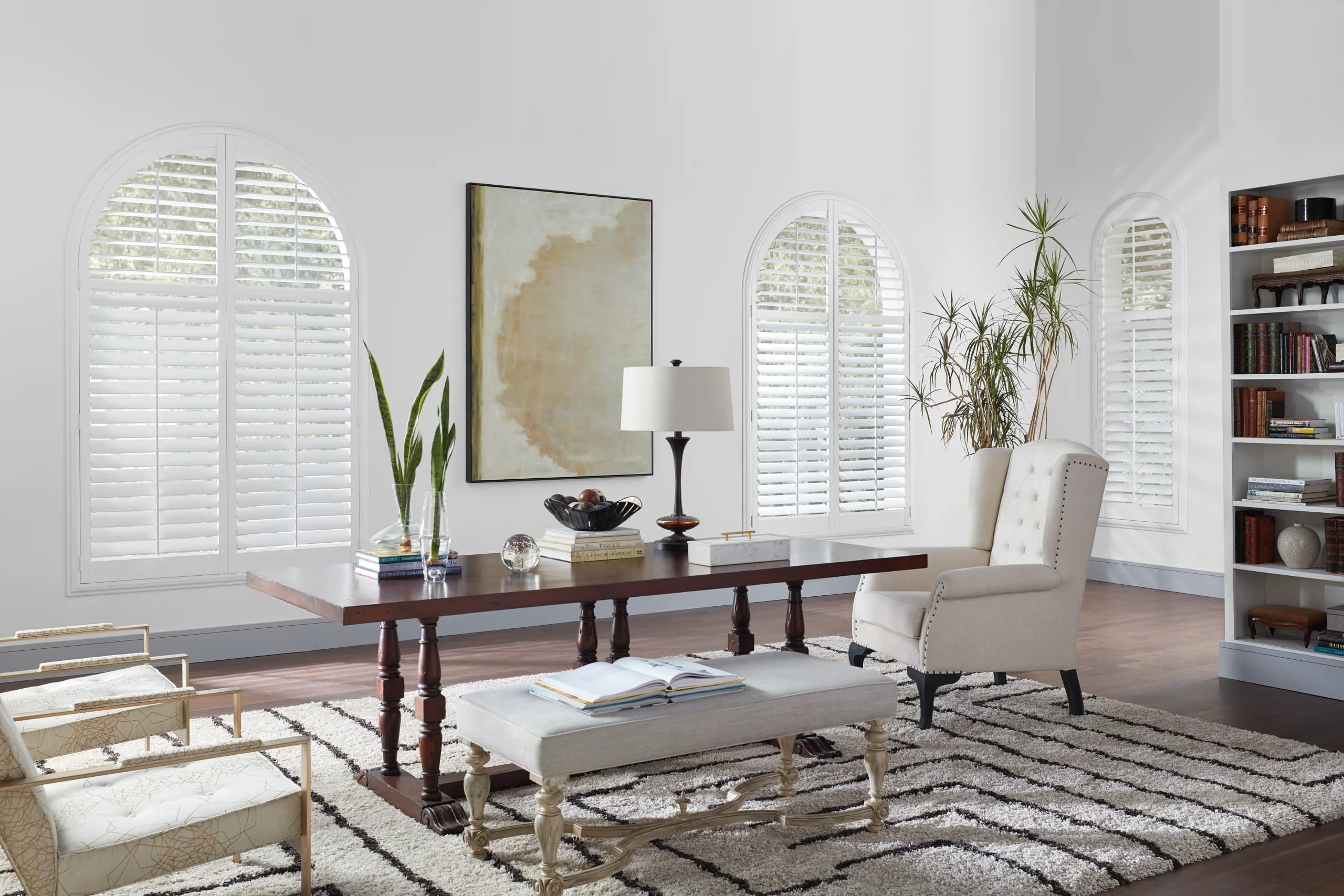 Hunter Douglas NewStyle® Hybrid Shutters with a front tilt bar on an arch top window in a library.
