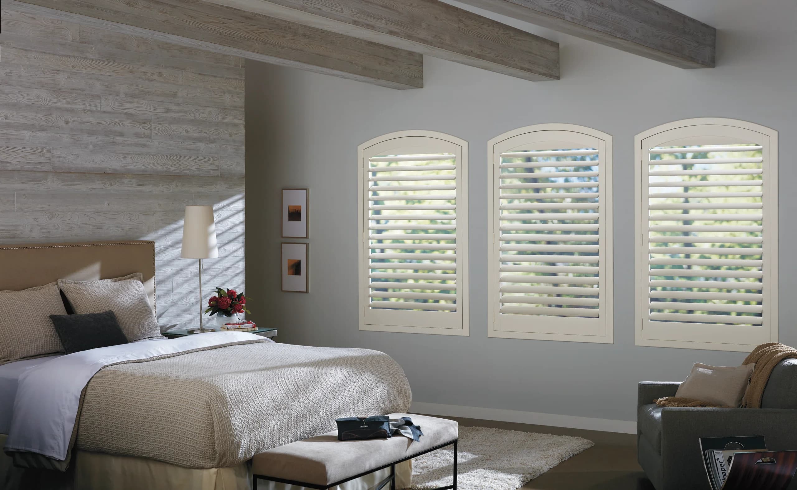 Hunter Douglas NewStyle® Hybrid Shutters under an arch top window in a bedroom.