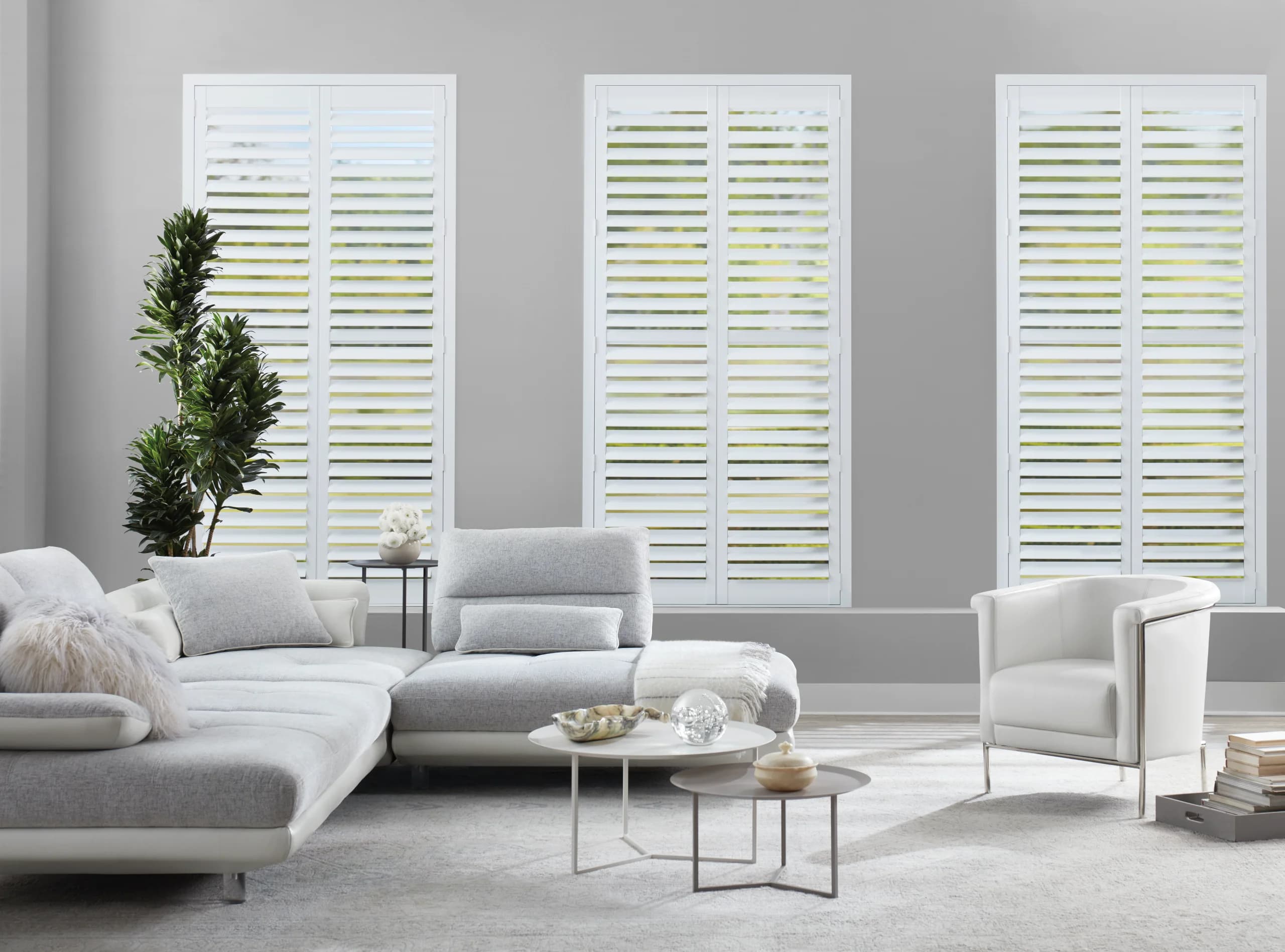 Hunter Douglas NewStyle® Hybrid Shutters on hinged panels across a living room window.