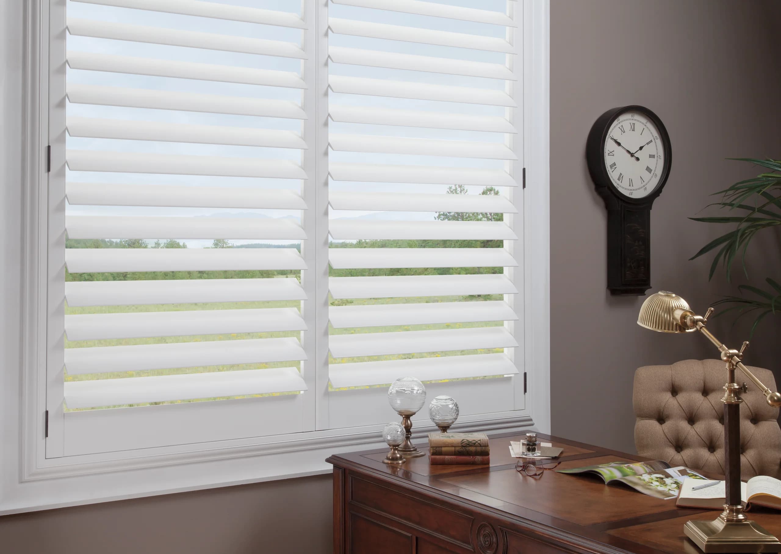 Hunter Douglas NewStyle® Hybrid Shutters filtering the light in a home office.