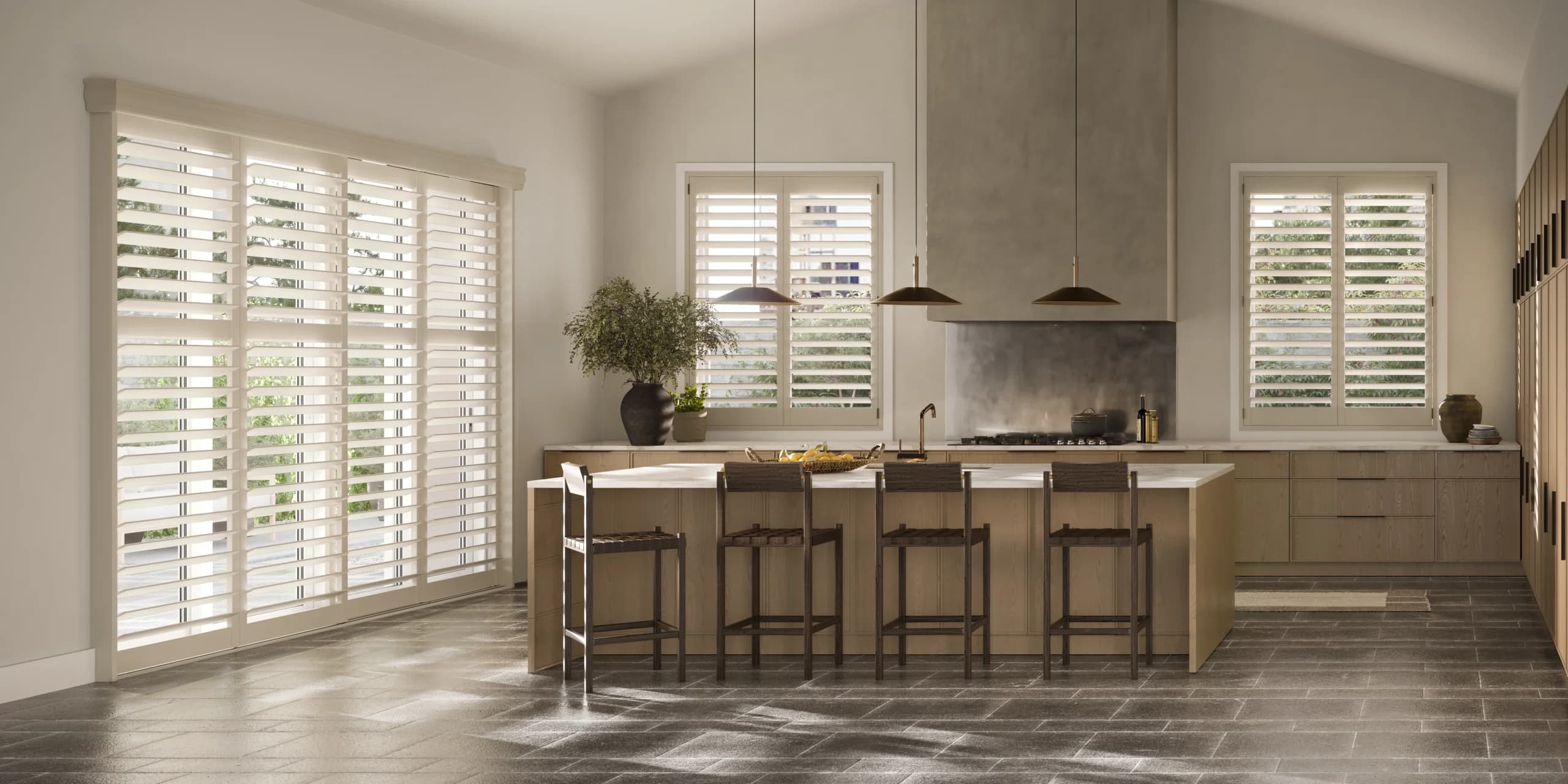 Hunter Douglas NewStyle® Hybrid Shutters in a sand tone in a kitchen, with a wide bypass track panel beside two smaller shuttered windows.