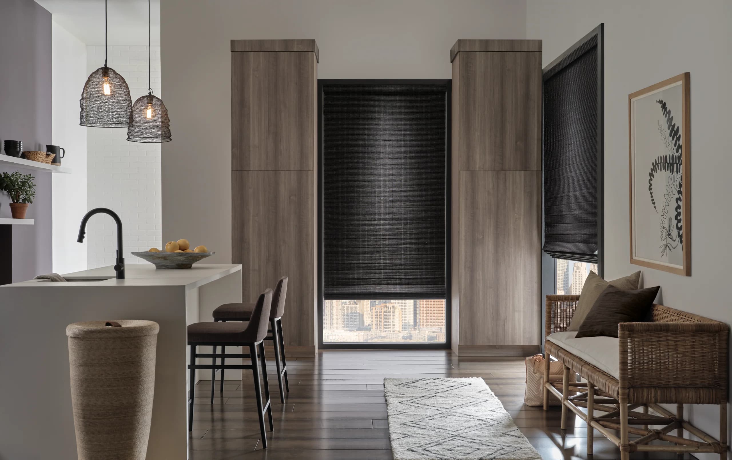 Black Provenance® Woven Wood Shades on a tall kitchen window and a corner window, with a city view showing beneath the hem.