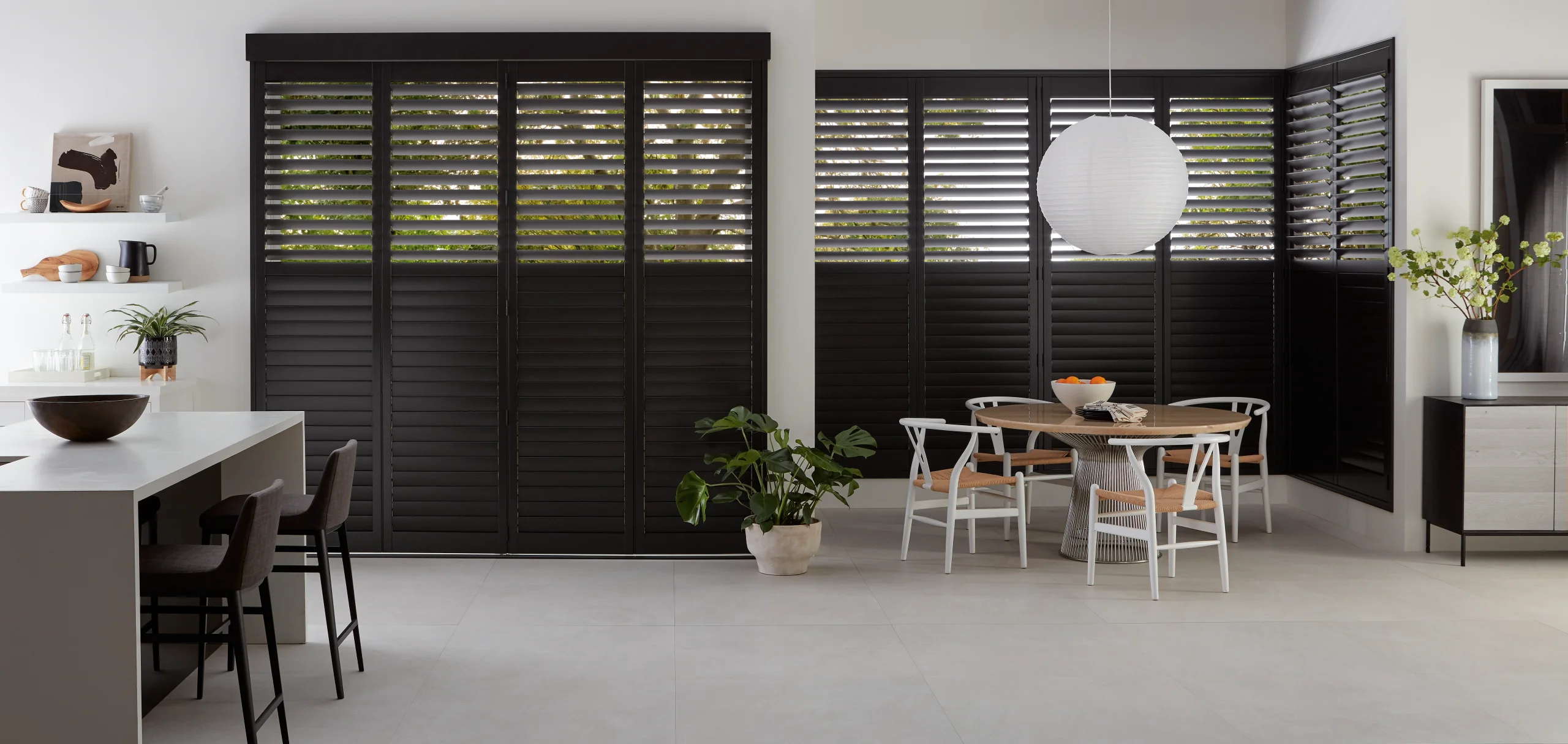 Custom Hunter Douglas plantation shutters on a bay window in a bright New England breakfast nook, measured and installed by Window Fantasies.