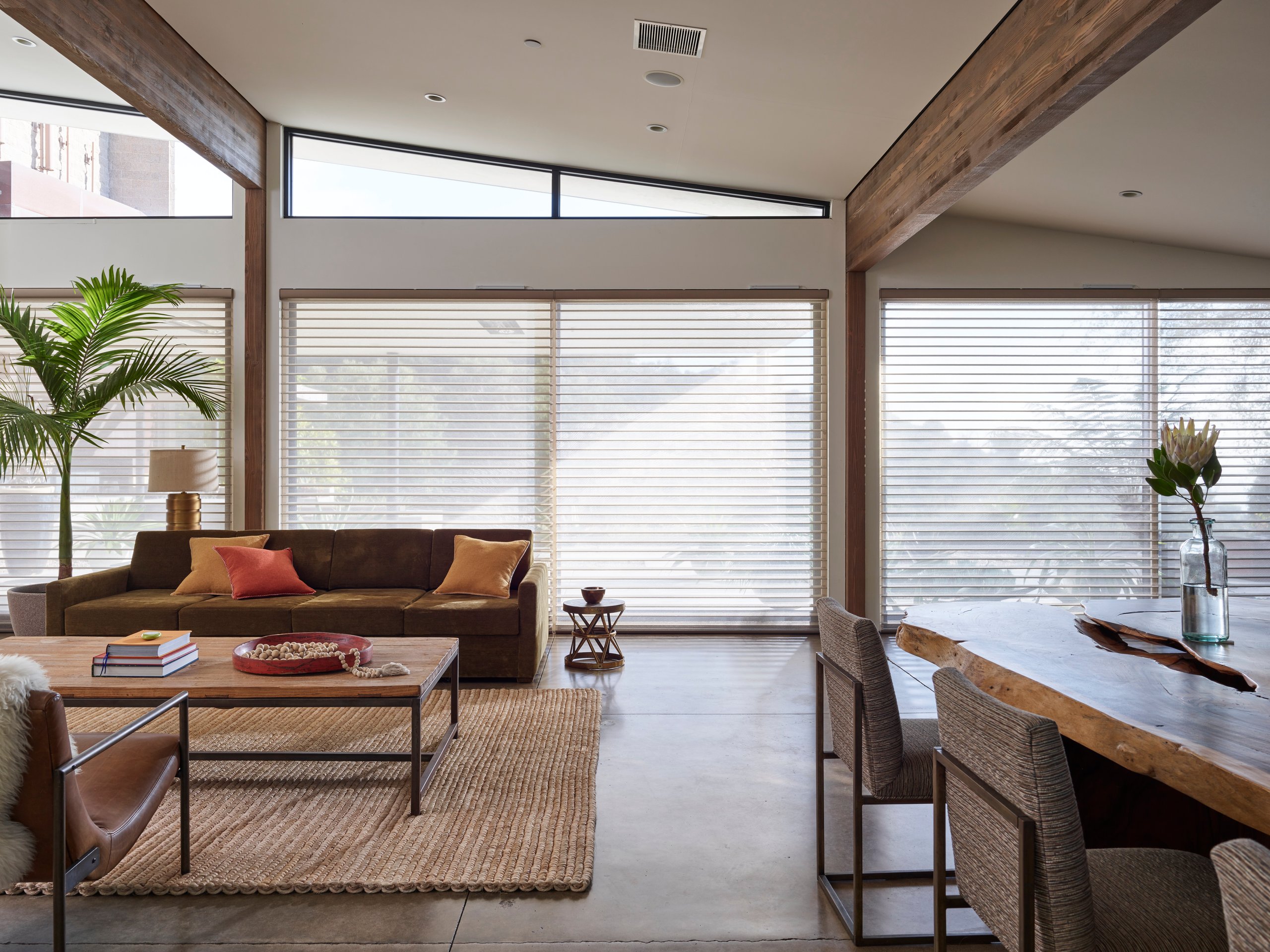 A luxury living room with golden light through sheer shades.