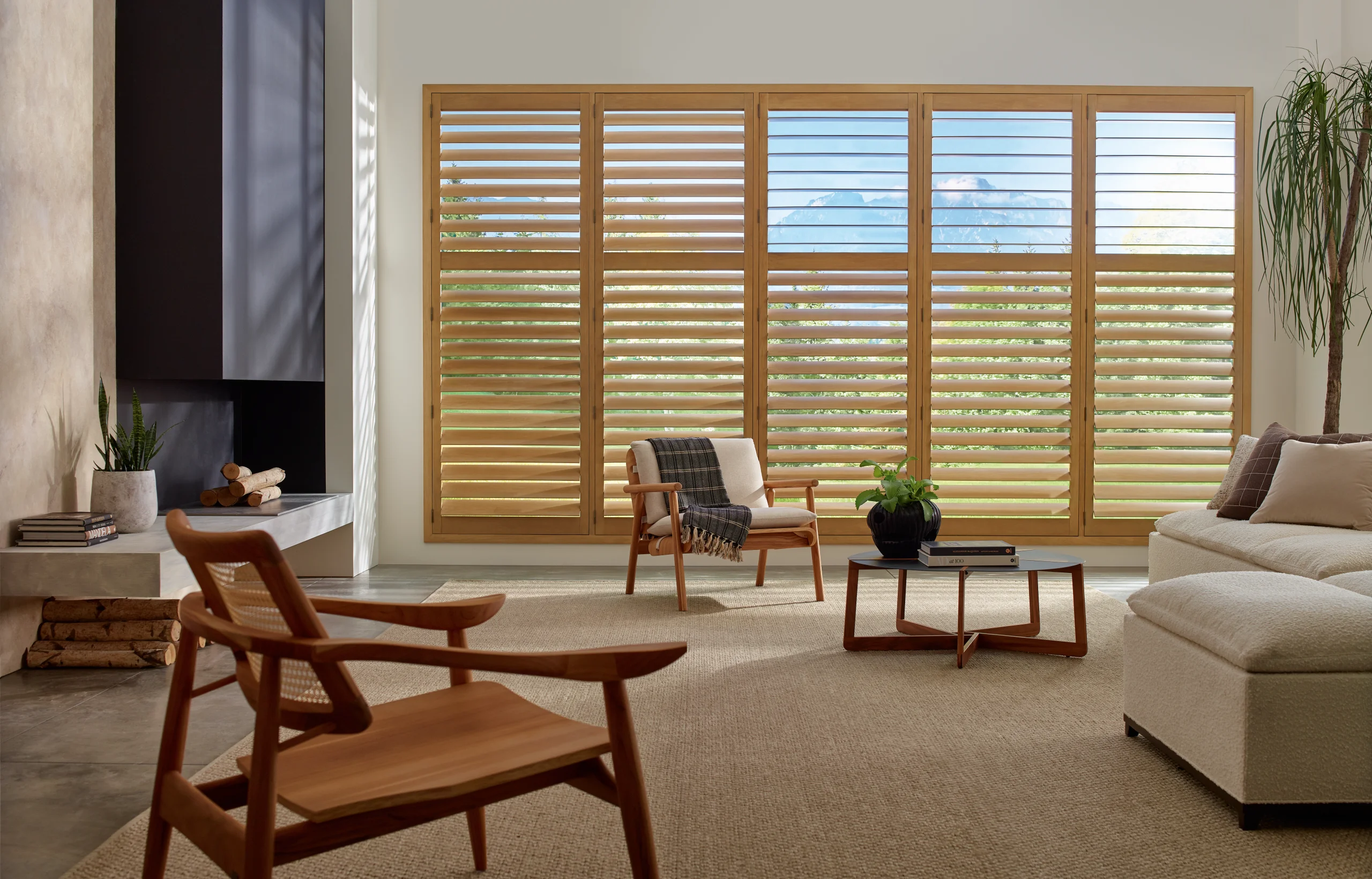 Hunter Douglas Heritance® Hardwood Shutters with the louvers open beside a reading chair in a living room.