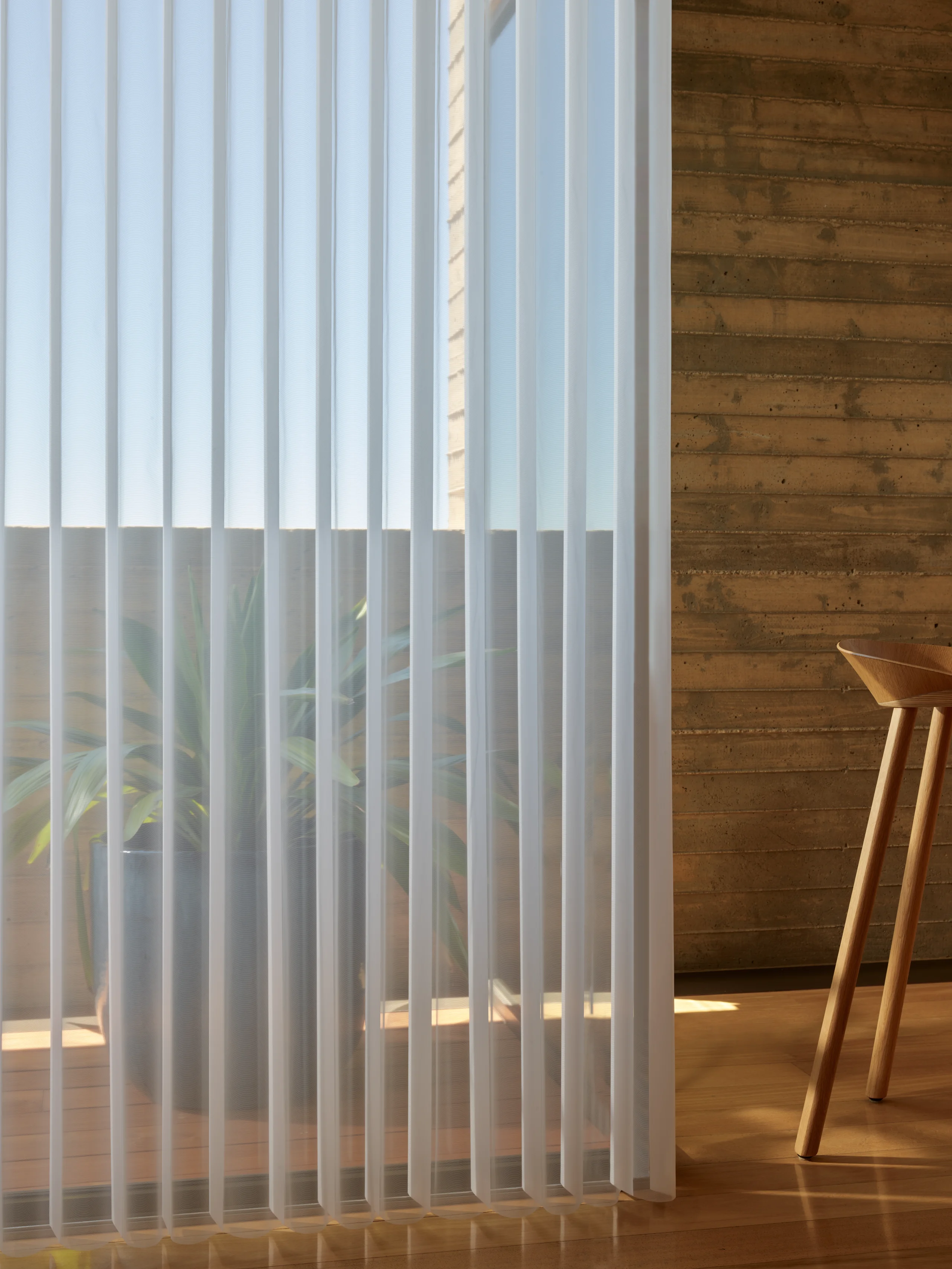 Close view of Hunter Douglas Luminette® Privacy Sheers, the vertical fabric vanes rotated to soften afternoon sun at a glass wall.