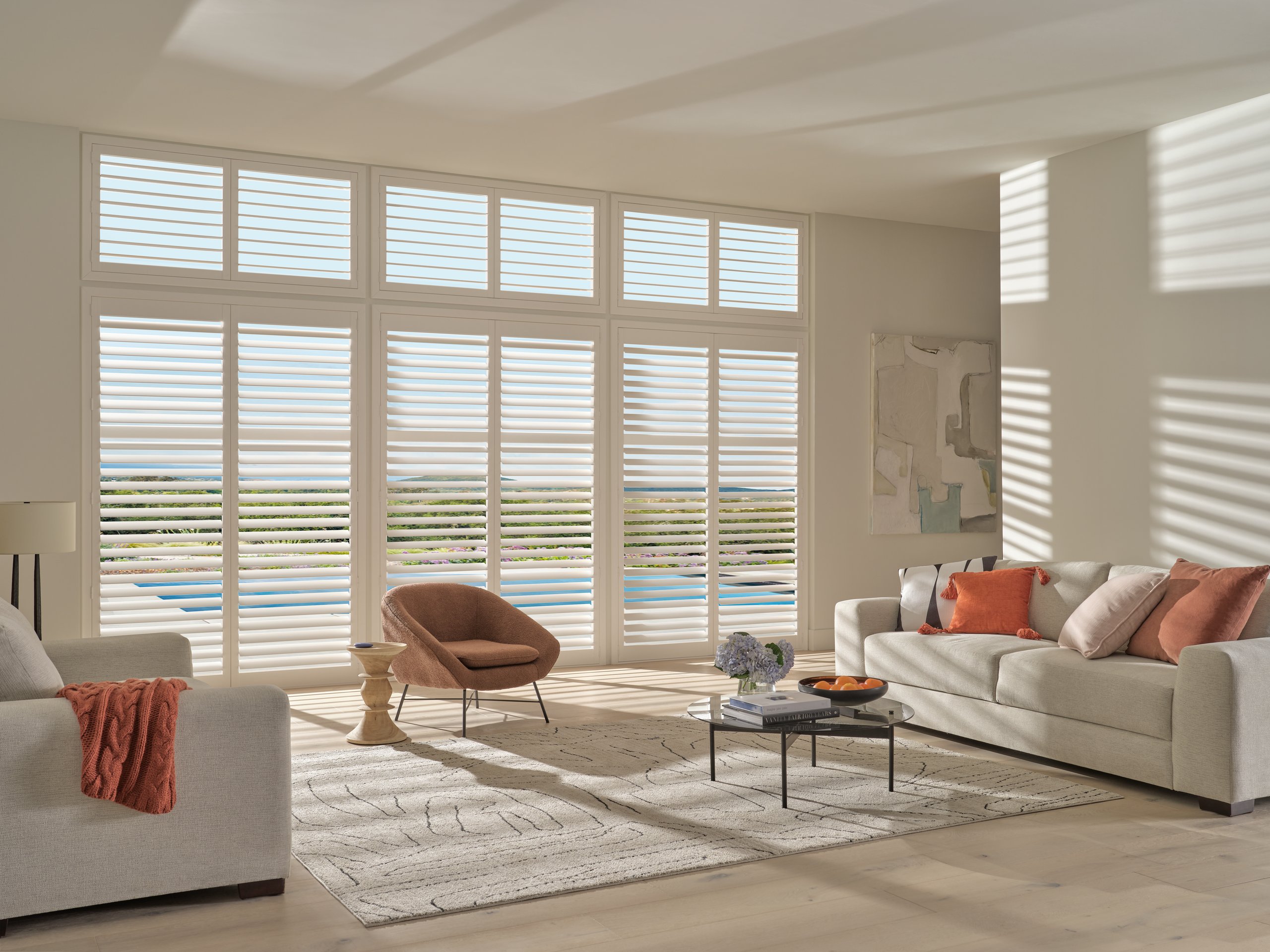 Hunter Douglas Palm Beach™ Polysatin™ Shutters in bright white across a living room window.