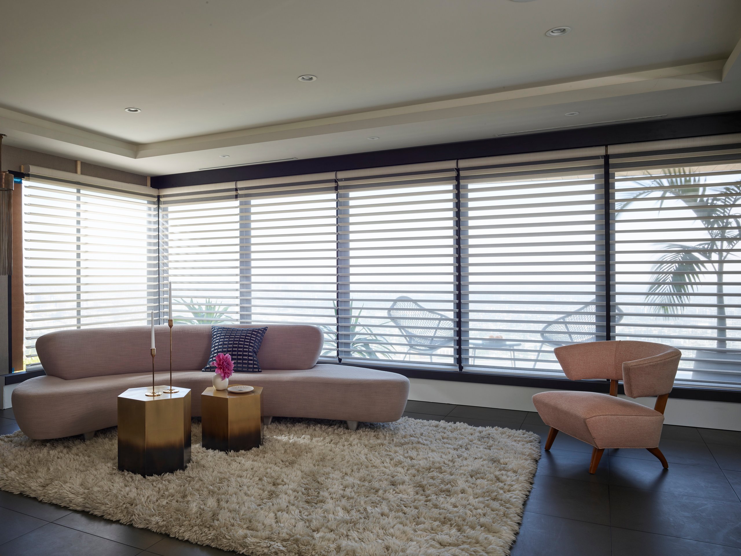 Hunter Douglas Silhouette® Window Shadings running the length of a corner window wall in a living room, vanes open to a hillside view.